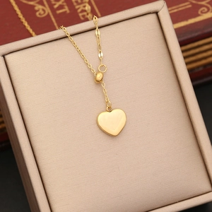 Detailed close-up of a golden heart pendant necklace on a champagne jewelry box display