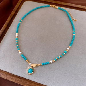 Detail view of turquoise beaded necklace with 18K gold-plated heart and zircon pendants