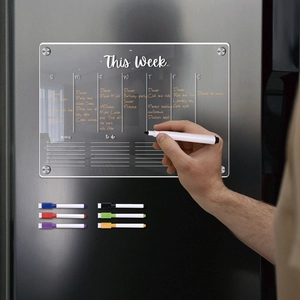 Detail of hand writing on a magnetic acrylic weekly planner on a refrigerator door