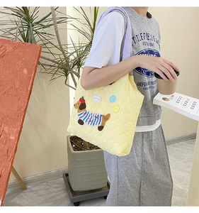 Detail of quilted yellow tote with cartoon dog embroidery and purple shoulder strap