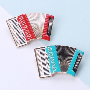 Detail view of red and turquoise enamel accordion brooches with gold metal accents