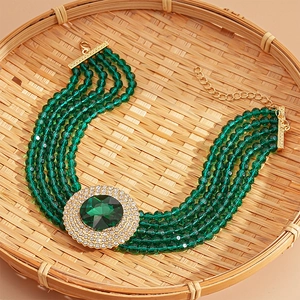 Detail of multi-layer green beaded necklace with luxury rhinestone pendant in bamboo tray