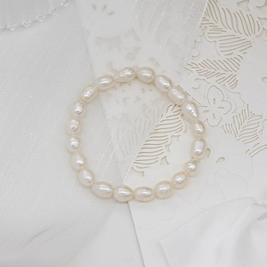 Detail of irregular freshwater pearls and jade bracelet on elegant white lace