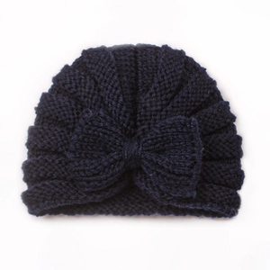 Detail of navy blue baby knitted beanie featuring a large bow and warm ripple texture