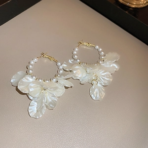 Detail of gold hoop earrings with white pearls and multilayered resin flower petals