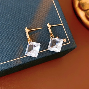Detail of gold square-cut crystal earrings on a blue textured display case