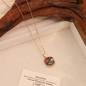 Detail of a purple flower pendant necklace with white pearl on a vintage wood display