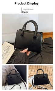 Detail view of black faux leather mini square bag with dual handles and slim shoulder strap