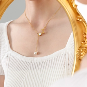 Gold tulip necklace with white shell flower and pearl pendant shown in mirror reflection