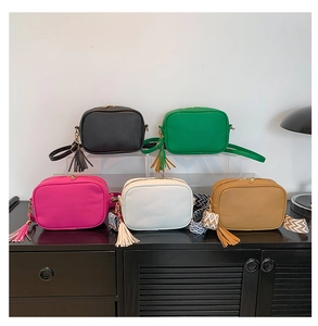 Detailed view of colorful leather camera bags with tassels and patterned straps