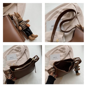 Close-up details of brown leather shoulder bag with adjustable strap and bunny pendant