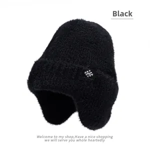 Détail du bonnet d'hiver noir à oreillettes avec texture peluche et flocon de neige