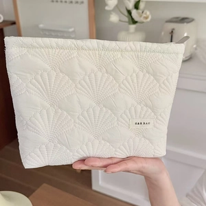 Detail of cream quilted shell makeup bag with H&R BAG label and soft fabric texture