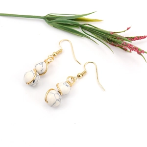 Detail of gold wire-wrapped earrings featuring marble texture white beads in boho style