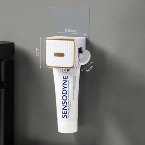 Wall-mounted white and gold manual toothpaste squeezer with minimalist hook design