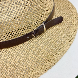 Detail of woven straw texture and dark brown leather strap with silver metal buckle