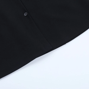 Détail d'un bouton noir sur une robe chemise ajustée à manches longues pour l'automne