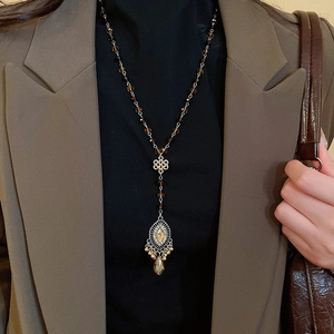 Close-up of vintage beaded necklace with hollow metal pendant and amber drop on a model
