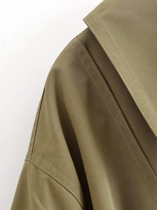 Close-up of olive green bomber jacket shoulder with durable twill fabric and stitching