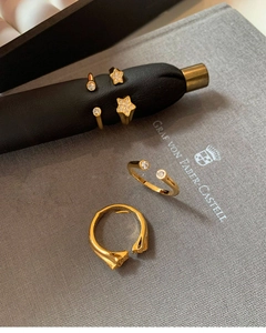 Detailed view of three gold-plated star rings and geometric bands with sparkling zircon