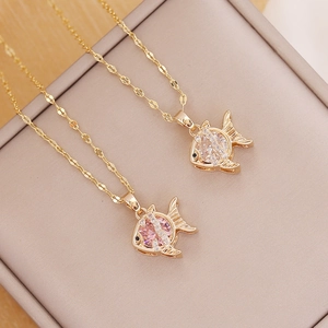 Detail of 18K gold fish necklaces with pink and white zircon in a beige jewelry box