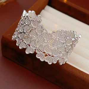 Macro shot of silver open cuff bracelet with cutout clover flower pattern on velvet case