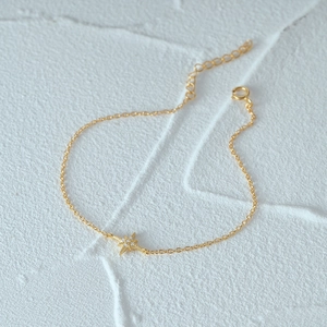 Close-up of golden octagonal star bracelet with sparkling zircon on white surface