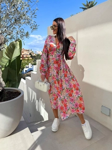 Detail of pink floral midi dress with V-neckline and long sleeves in outdoor lighting