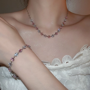 Close-up of model wearing sparkling pink and clear zircon pendant necklace and bracelet set