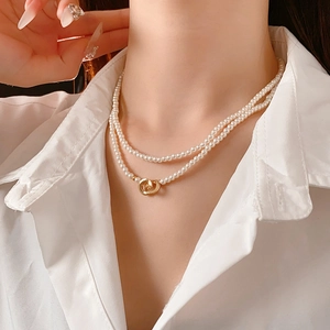 Detail of double-layer pearl necklace with a golden ring pendant worn by a model