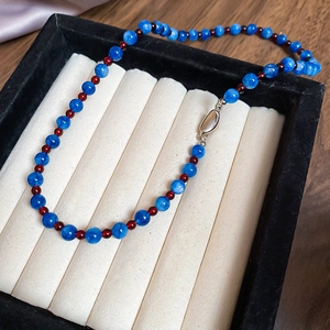 Detailed close-up of blue stone beads and red spacers on a handcrafted beaded necklace