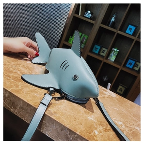 Detailed view of the 3D shark-shaped crossbody bag on a textured marble counter