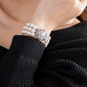 Detail of multi-layer pearl bracelet with rhinestone flower clasp worn on wrist