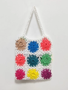 Detail view of handmade crochet tote bag featuring vibrant colorful 3D floral appliques