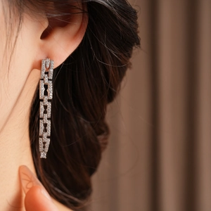 Détail de boucles d'oreilles pendantes en argent avec zircons portées par un mannequin