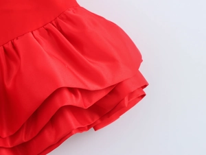 Détail du bord à volants en satin rouge et de la texture du tissu superposé de ce haut chic