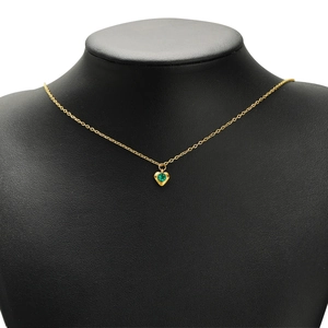 Golden necklace with a heart-shaped green gemstone pendant on a black mannequin display