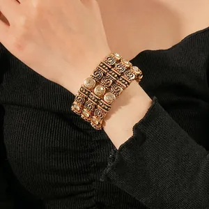 Vintage gold cuff bracelet with spiral patterns and inlaid diamonds on a model arm