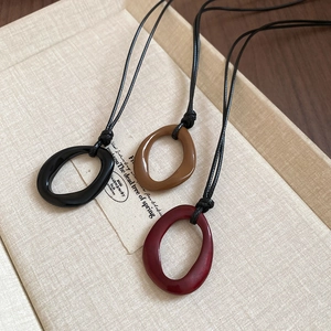 Détail de pendentifs ovales en résine colorée sur cordons noirs exposés sur des boîtes