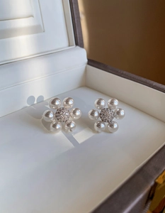 Gros plan de boucles d'oreilles fleur en perles avec centre en zircone et boîte