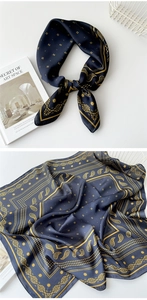Detail of navy blue silk scarf with golden paisley patterns and smooth glossy texture