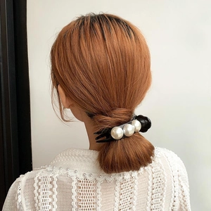 Pince à cheveux noire élégante avec grandes perles sur une femme coiffée en chignon