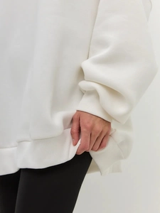 Detail view of white fleece sweatshirt showing ribbed cuffs and soft cotton texture