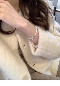 Detail of s925 silver lucky tag and white freshwater pearls on a model wrist
