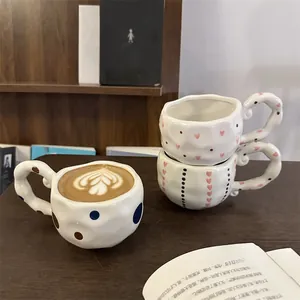 Detail of irregular textured ceramic coffee mugs with cute patterns on a wooden table