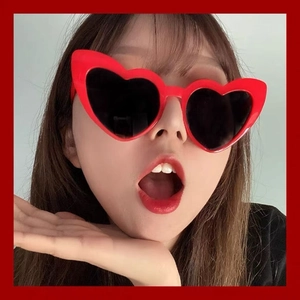 Detail view of red heart-shaped sunglasses with dark lenses on a female model