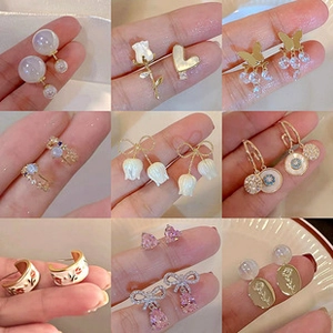Détail de neuf paires de boucles d'oreilles avec perles, fleurs et breloques papillons