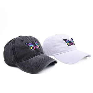 Detailed view of colorful butterfly embroidery on washed grey and white baseball caps