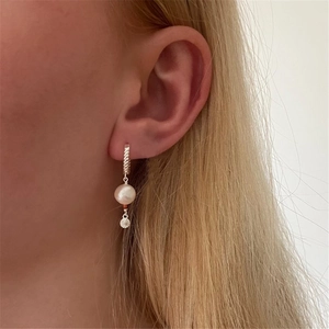Close-up of model wearing 925 silver twisted hoop earrings with white pearls and metal discs