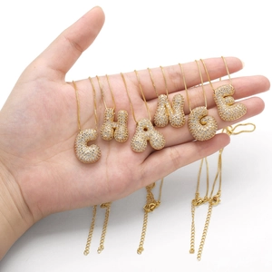 Macro shot of 3D bubble gold letter pendants spelling CHANGE with white zircon stones